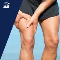 Ein sportlicher Mann fasst sich auf seinen Oberschenkel.