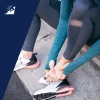 Eine Frau mit einem Fusskrampf beim Laufen